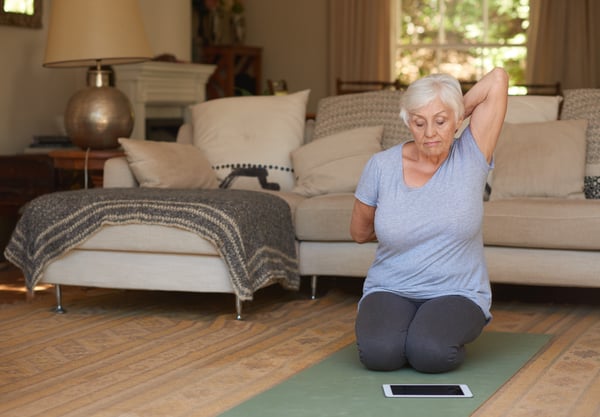 Elderly woman exercising at home with telehealth tablet