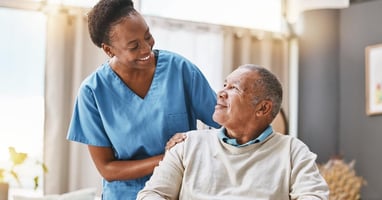 A home health nurse helps care for a patient in a wheelchair in their home