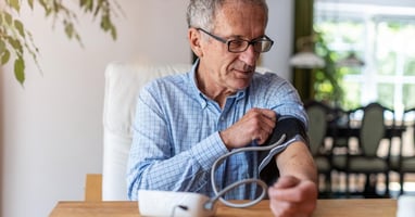 A man with hypertension takes a blood pressure reading from home using remote patient monitoring (RPM) technology