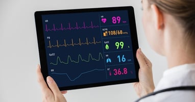 A telehealth nurse holding a tablet with patient vitals from a remote monitoring program