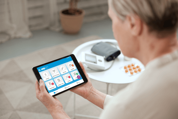 Photo of an RPM patient holding a tablet with the HRS RPM Dashboard displayed